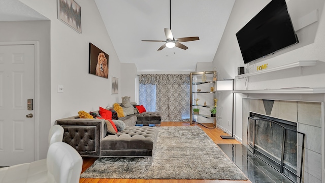 living room with hardwood / wood-style floors, ceiling fan, lofted ceiling, and a tile fireplace