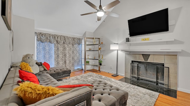 living room featuring a tile fireplace, hardwood / wood-style floors, high vaulted ceiling, and ceiling fan