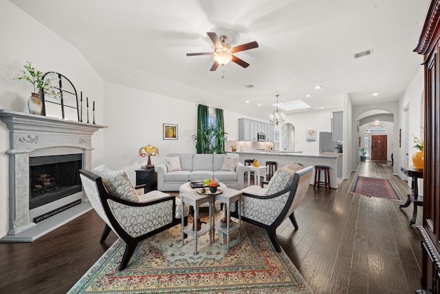 living room with ceiling fan with notable chandelier and dark hardwood / wood-style flooring