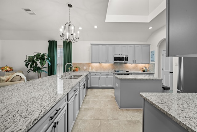 kitchen with decorative backsplash, light stone counters, sink, and appliances with stainless steel finishes