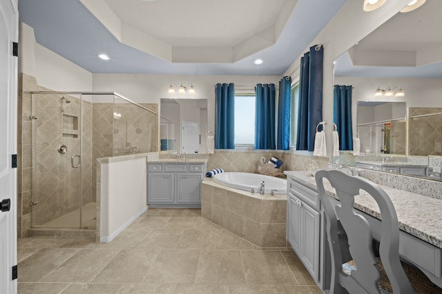 bathroom featuring a tray ceiling, separate shower and tub, and vanity