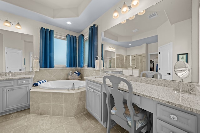 bathroom with tile patterned flooring, vanity, a tray ceiling, and independent shower and bath