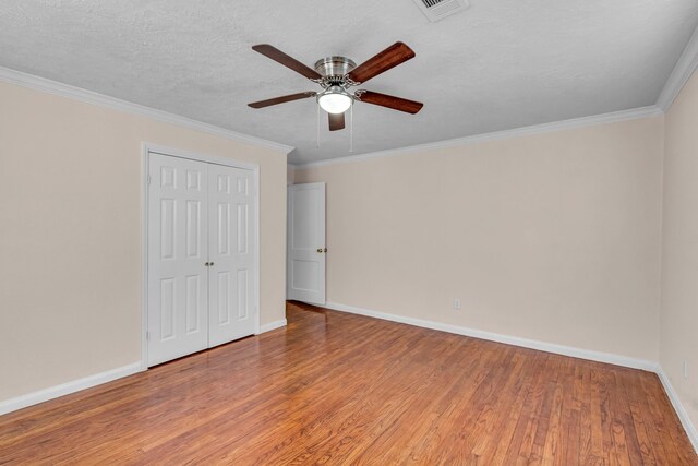 unfurnished bedroom featuring hardwood / wood-style floors, a textured ceiling, ceiling fan, and crown molding