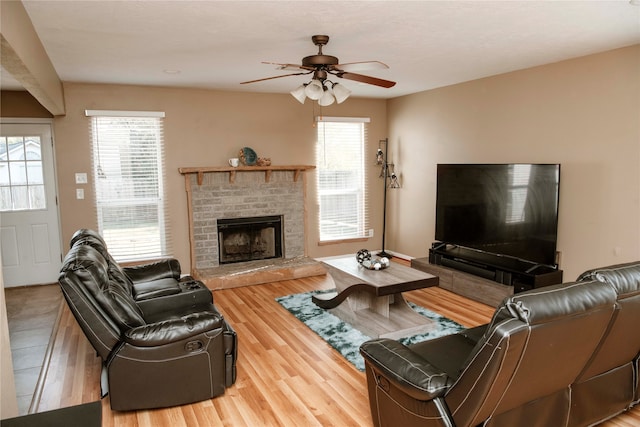 living room featuring hardwood / wood-style floors, a brick fireplace, and ceiling fan