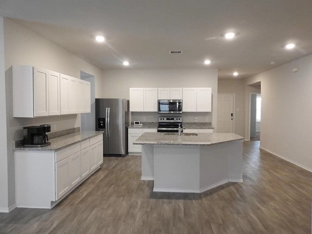 kitchen with dark hardwood / wood-style flooring, a center island with sink, white cabinets, and appliances with stainless steel finishes