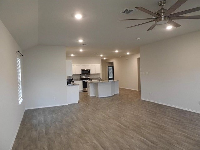 unfurnished living room with ceiling fan, hardwood / wood-style floors, and lofted ceiling