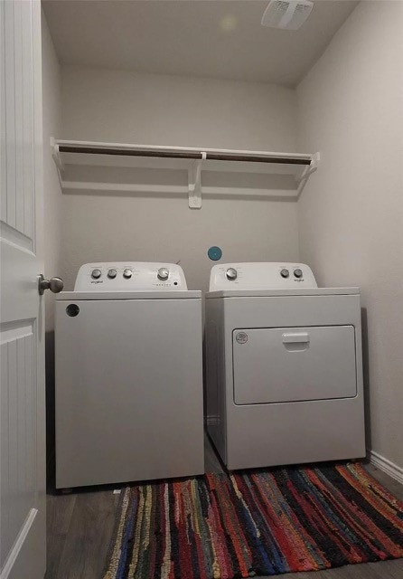 washroom with dark hardwood / wood-style flooring and washing machine and dryer