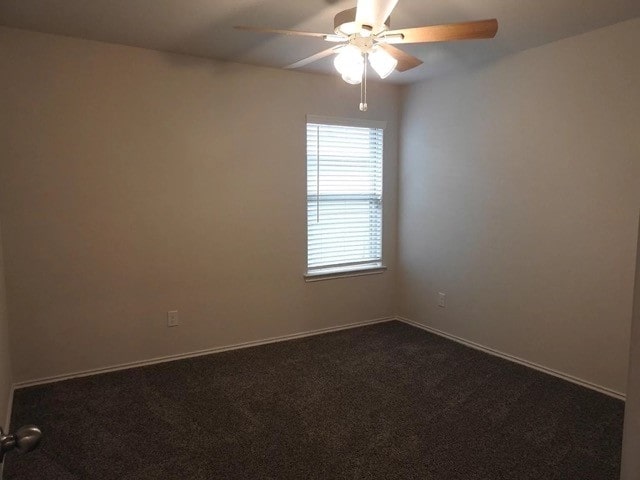 spare room featuring dark colored carpet and ceiling fan