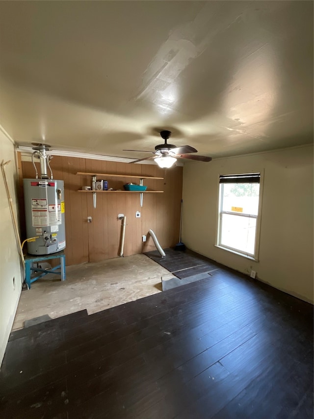 interior space featuring water heater, ceiling fan, and wood walls