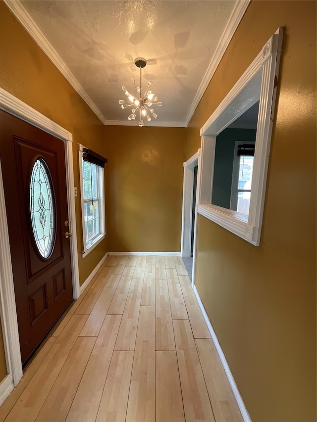 foyer with crown molding, plenty of natural light, a notable chandelier, and light wood-type flooring