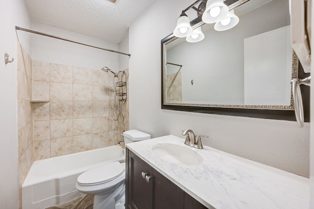 full bathroom featuring toilet, vanity, a textured ceiling, and tiled shower / bath