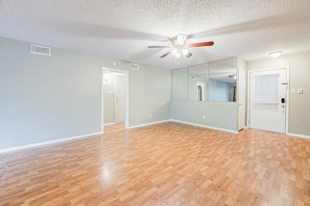 unfurnished room with ceiling fan, light wood-type flooring, and a textured ceiling