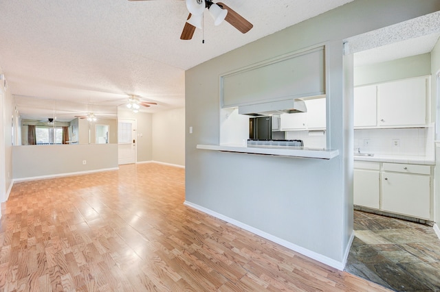 unfurnished living room with a textured ceiling, light hardwood / wood-style flooring, and ceiling fan