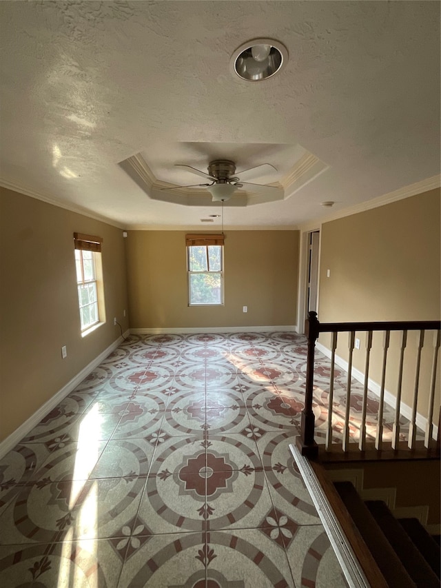 unfurnished room featuring a raised ceiling, a wealth of natural light, and ornamental molding