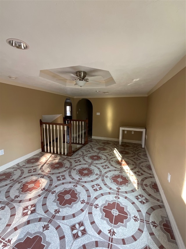 interior space with a raised ceiling and ceiling fan