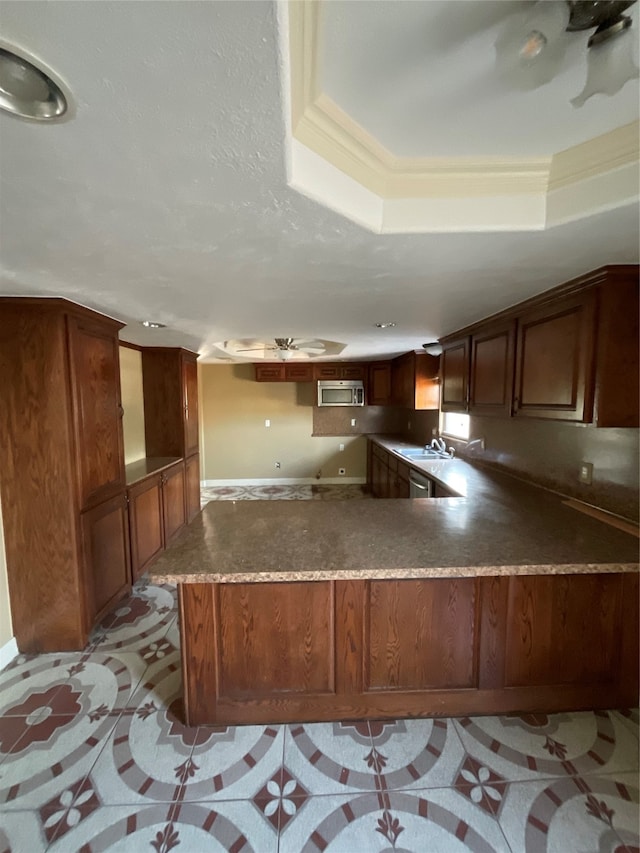 kitchen featuring kitchen peninsula, a raised ceiling, ornamental molding, and sink