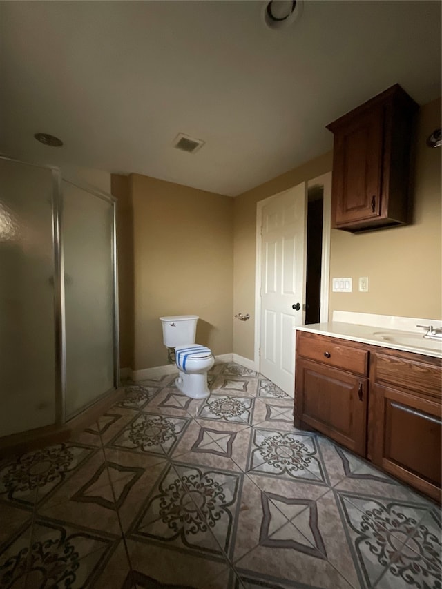 bathroom with tile patterned floors, vanity, a shower with shower door, and toilet