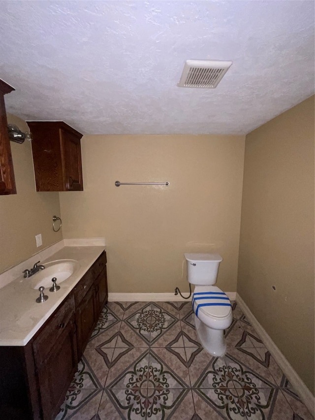 bathroom featuring tile patterned flooring, vanity, toilet, and a textured ceiling