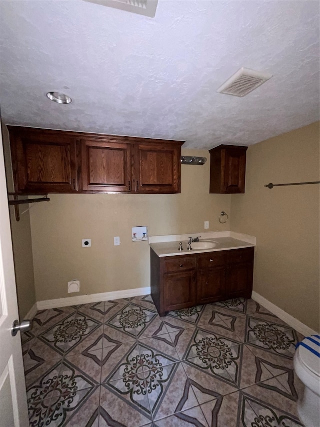 interior space with sink, hookup for an electric dryer, hookup for a washing machine, a textured ceiling, and light tile patterned floors