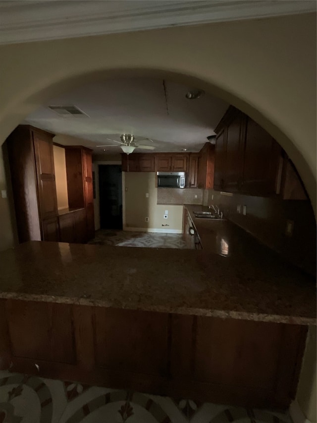 kitchen featuring ceiling fan, sink, kitchen peninsula, and crown molding