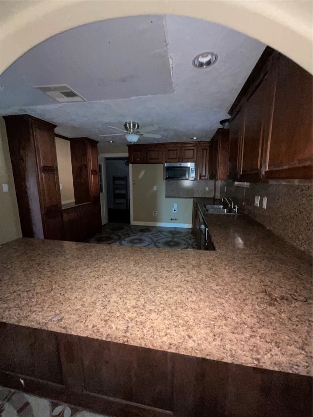 kitchen featuring backsplash, dark brown cabinetry, and sink