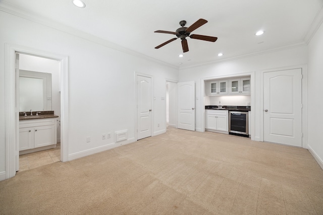 unfurnished living room featuring light colored carpet, beverage cooler, ornamental molding, and ceiling fan