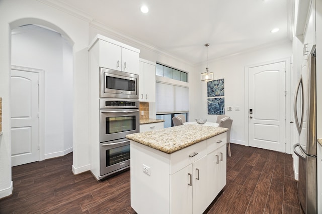 kitchen featuring appliances with stainless steel finishes, decorative light fixtures, white cabinets, a center island, and crown molding