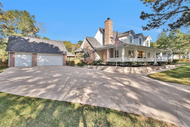 view of front facade featuring a porch, a front lawn, an outdoor structure, and a garage