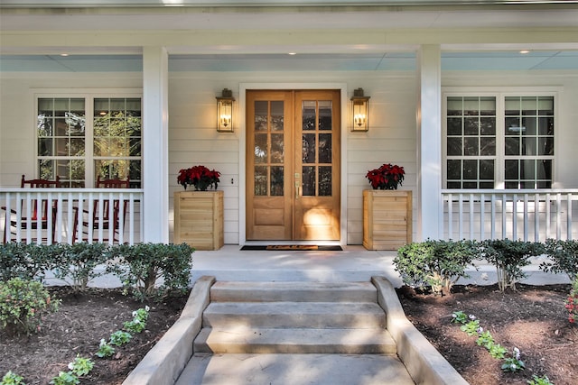 view of exterior entry featuring covered porch and french doors