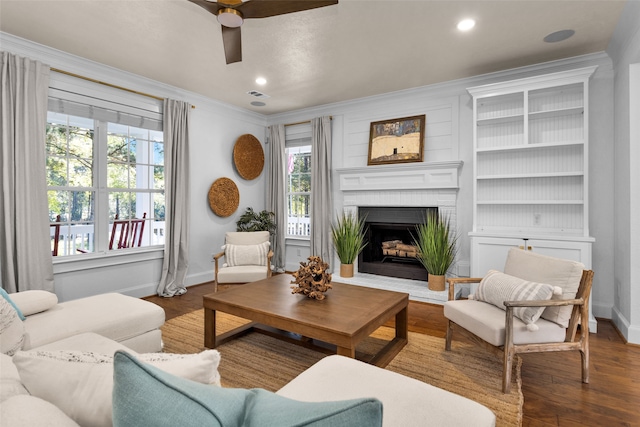 living room with ceiling fan, wood-type flooring, a healthy amount of sunlight, and a brick fireplace