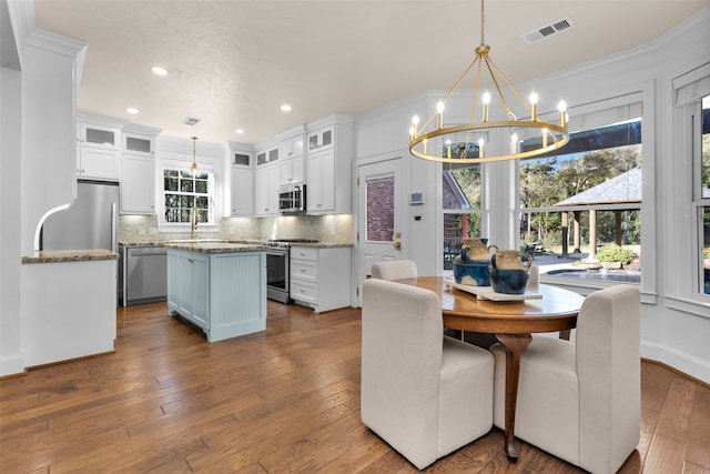 dining area featuring hardwood / wood-style flooring, ornamental molding, sink, and a chandelier