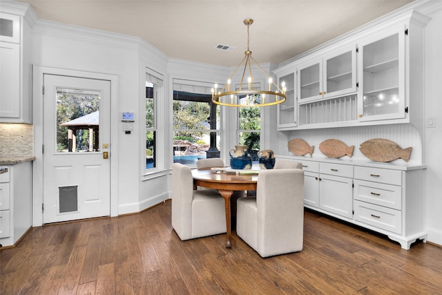 dining space with a chandelier, crown molding, and dark wood-type flooring