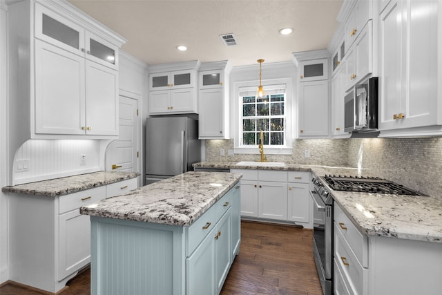 kitchen with pendant lighting, a center island, white cabinets, sink, and appliances with stainless steel finishes