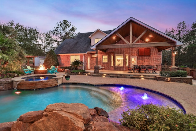 pool at dusk featuring a patio and a fire pit