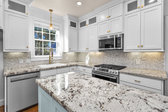 kitchen featuring tasteful backsplash, stainless steel appliances, sink, decorative light fixtures, and white cabinets