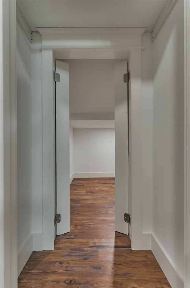 corridor with baseboards and wood finished floors