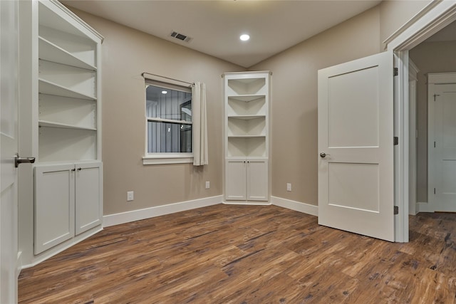 unfurnished room with visible vents, baseboards, and dark wood-type flooring