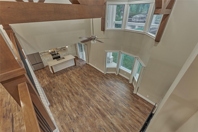 entryway featuring baseboards, a high ceiling, wood finished floors, and a ceiling fan