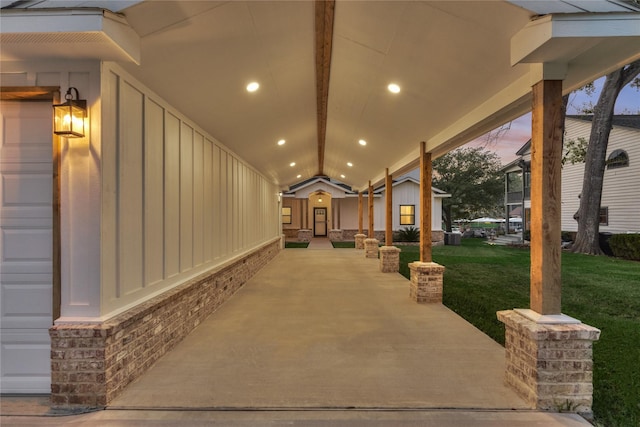 patio terrace at dusk featuring a lawn and a garage