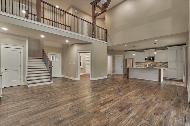 unfurnished living room featuring stairs, dark wood-type flooring, recessed lighting, and baseboards