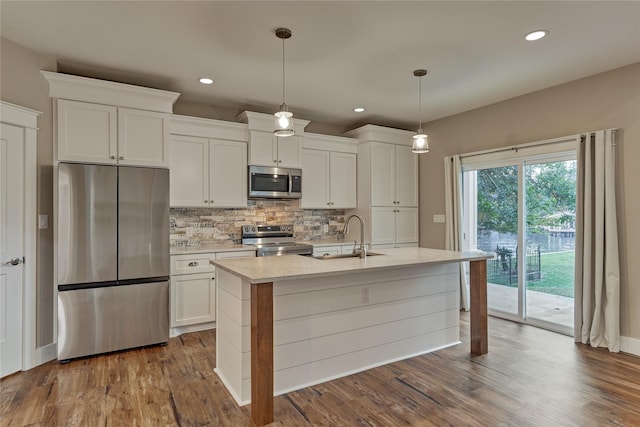 kitchen featuring dark wood finished floors, a sink, stainless steel appliances, white cabinets, and tasteful backsplash