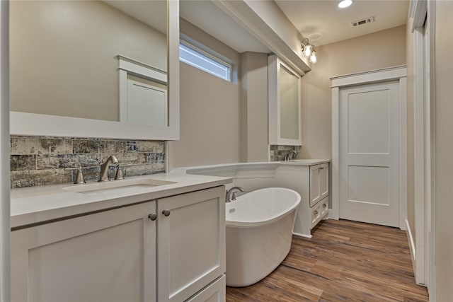 bathroom with wood finished floors, visible vents, backsplash, and a sink