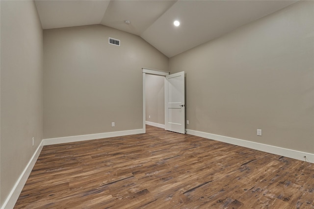 empty room featuring visible vents, dark wood-type flooring, baseboards, and vaulted ceiling