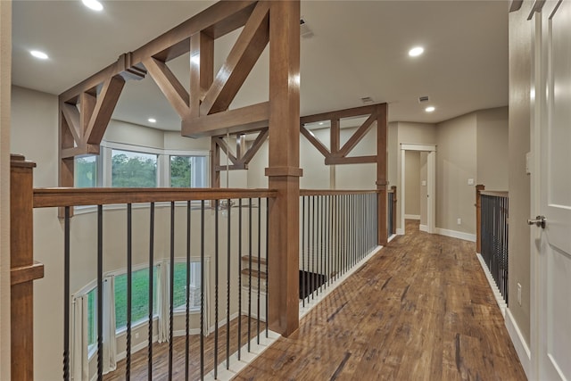 corridor with recessed lighting, baseboards, wood finished floors, and an upstairs landing