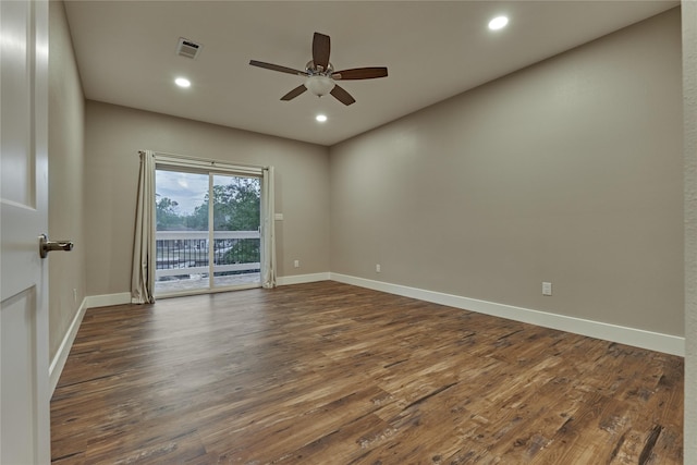 spare room featuring dark wood-style floors, a ceiling fan, visible vents, and baseboards