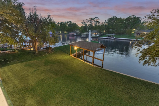 view of dock featuring a lawn, a water view, and boat lift