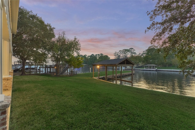 view of dock with a yard and a water view