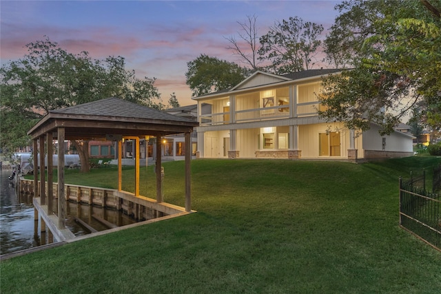 back of house at dusk featuring a yard and a water view