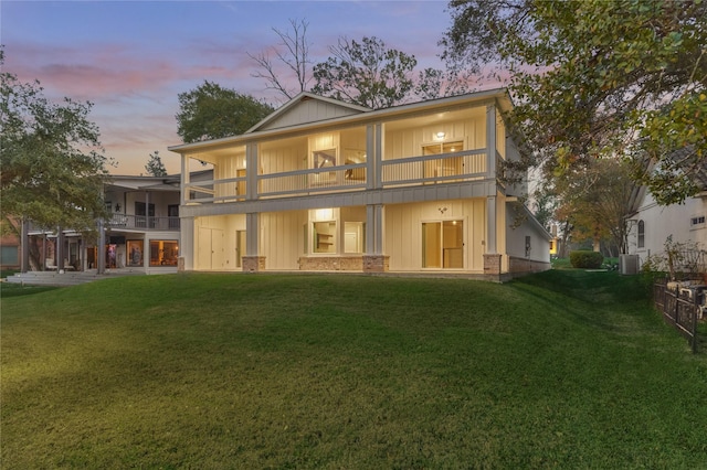 back of house with a balcony, a yard, central AC unit, and brick siding