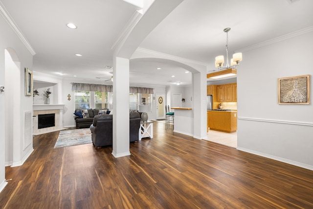 living room with hardwood / wood-style flooring, a fireplace, crown molding, and ceiling fan with notable chandelier